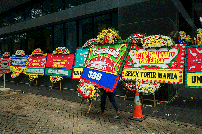 Pekerja melintas dekat karangan bungan di halaman kantor PSSI, Senayan, Jakarta, Kamis (30/3/2023).
