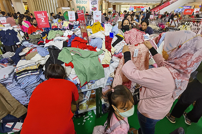 Pengunjung saat memilih pakaian yang dijual diskon di Pusat Perbelanjaan, Jakarta, Minggu (2/4/2023).