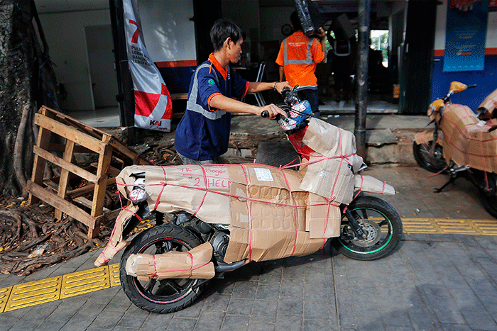 Pekerja tengah mengepak sepeda motor yang akan di kirim melalui jasa pengiriman dengan kereta api di Kawasan Stasiun Senen, Jakarta, Senin (17/4/2023).