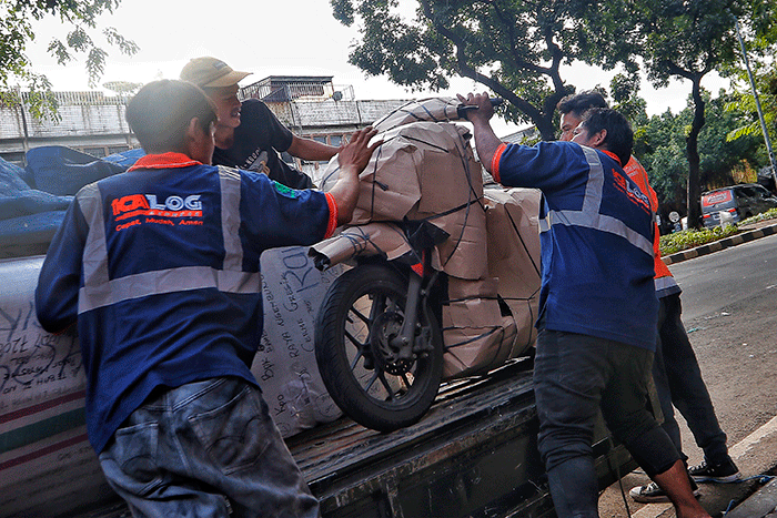 Pekerja tengah mengepak sepeda motor yang akan di kirim melalui jasa pengiriman dengan kereta api di Kawasan Stasiun Senen, Jakarta, Senin (17/4/2023).