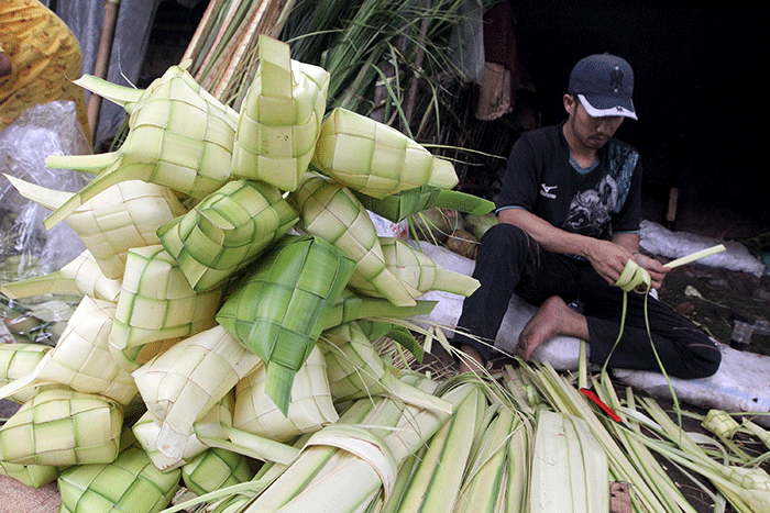 Pedagang kulit ketupat membuat ketupat di kawasan Palmerah, Jakarta, Jumat (21/4/2023).