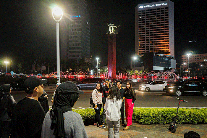 Sejumlah warga berswafoto di kawasan Bundaran HI, Jakarta, Minggu (23/4/2023).