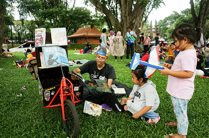 Seorang anak membaca buku gratis yang digelar oleh Kargo Baca di Taman Mini Indonesia Indah (TMII), Jakarta, Minggu (23/4/2023).