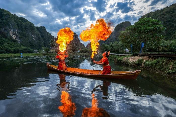 Dua penari Pepe Ri Makka beraktraksi di atas sampan sambil menyemburkan api dan difoto oleh sejumlah fotografer.