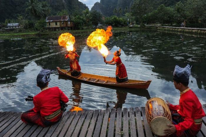 Dua penari Pepe Ri Makka beraktraksi di atas sampan sambil menyemburkan api dan difoto oleh sejumlah fotografer