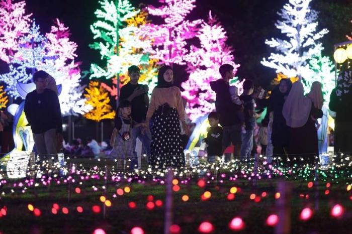 Warga menikmati warna-warni cahaya di area Makassar Light Festival Lapangan Hasanuddin, Makassar, Sulawesi Selatan, Minggu (11/6/2023).