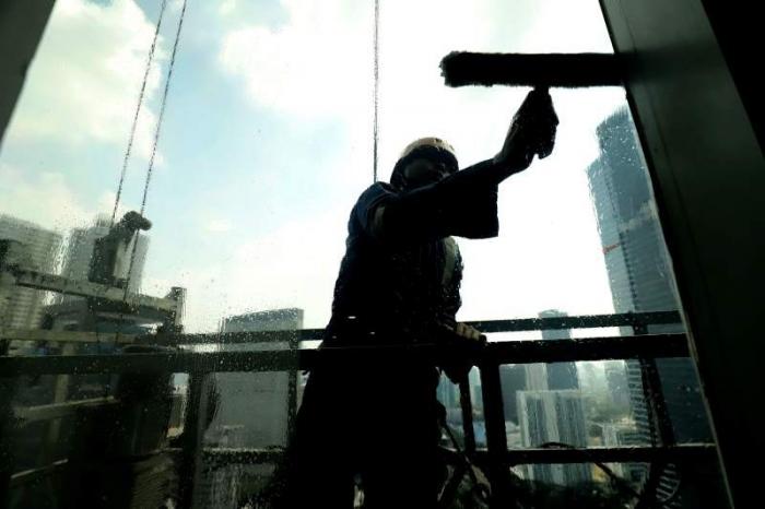 Pekerja menggunakan perlengkapan keamanan lengkap melakukan perawatan gedung bertingkat di Jakarta, Jumat (23/6/2023).