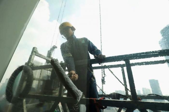 Pekerja menggunakan perlengkapan keamanan lengkap melakukan perawatan gedung bertingkat di Jakarta, Jumat (23/6/2023).