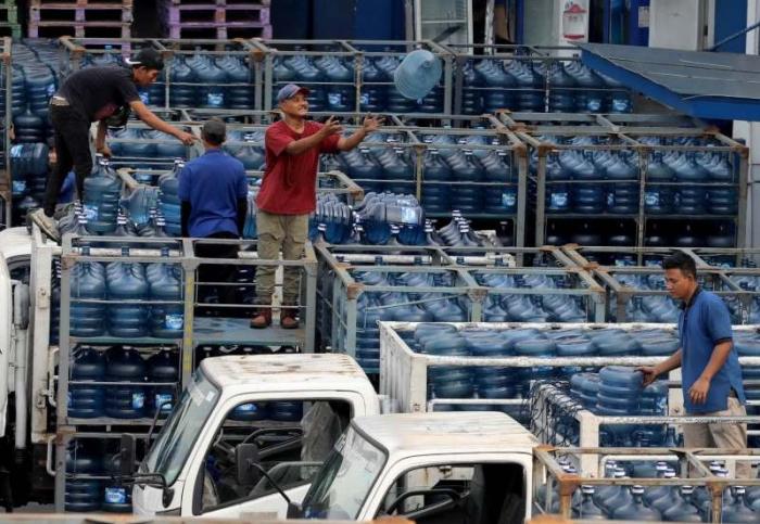 Pekerja melakukan bongkar muat air minum dalam kemasan di Jakarta, Jumat (30/6/2023).