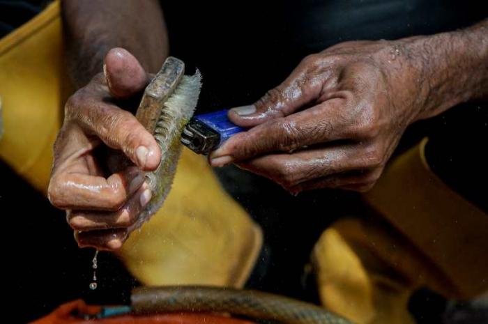 Timan memanfaatkan limbah korek api gas untuk dijadikan kerajinan tangan miniatur di Pos UPS Badan Air Kali Utan Kayu