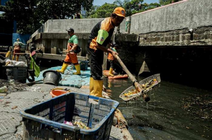 Timan mengumpulkan limbah korek api gas dari sampah Kali Utan Kayu