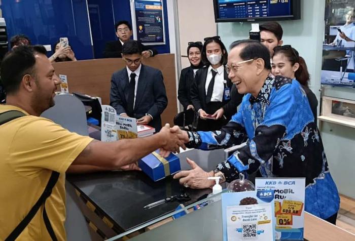 Presiden Direktur BCA Jahja Setiaatmadja menyerahkan cenderamata kepada nasabah di BCA KCU City Tower, Jakarta, Senin (4/9/2023).