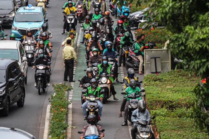 Pengendara ojek online melintas di kawasan Sudirman, Jakarta, Senin (23/10/2023).