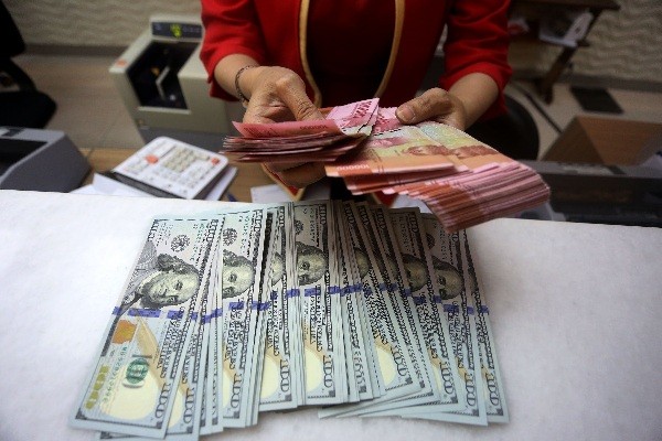 Karyawati menunjukkan mata uang rupiah dan dolar Amerika Serikat di tempat penukaran uang asing Agung Masayu di Jakarta, Selasa (24/10/2023).